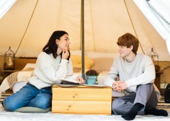 A young couple enjoying a luxury yurt featuring a cosy bed and a large, clear skylight for viewing the night sky from the comfort of the room