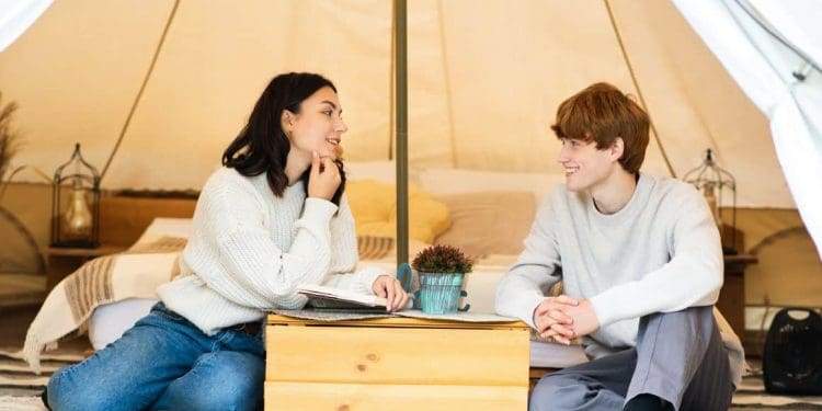A young couple enjoying a luxury yurt featuring a cosy bed and a large, clear skylight for viewing the night sky from the comfort of the room