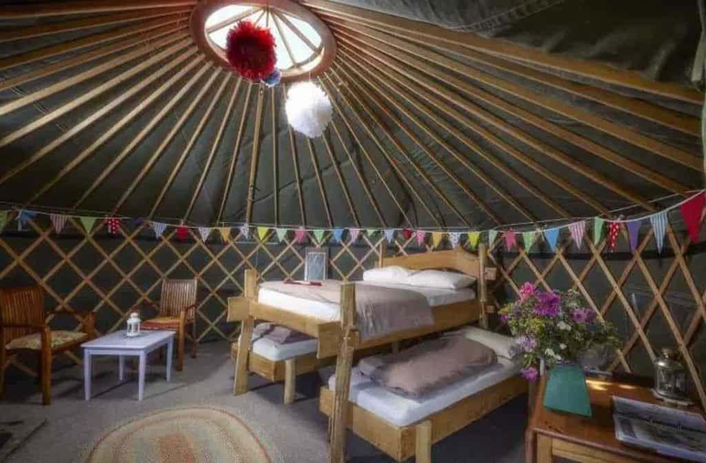 Several traditional yurts nestled among lush greenery and rolling hills, providing a serene and idyllic setting for a glamping adventure.