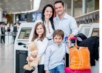 A family with luggage standing near a van, ready for airport transfer.