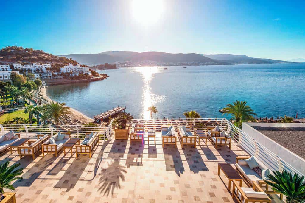 This image captures the serene elegance of Prive Bodrum, a luxurious retreat on the shores of the Mediterranean. The photograph showcases a stunning beachfront setting, where the azure waters of the sea gently kiss the pristine, sandy shore.