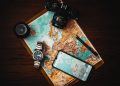 Travel essentials including a passport, boarding pass, compact luggage, and headphones arranged on a map, symbolizing thorough travel preparation.