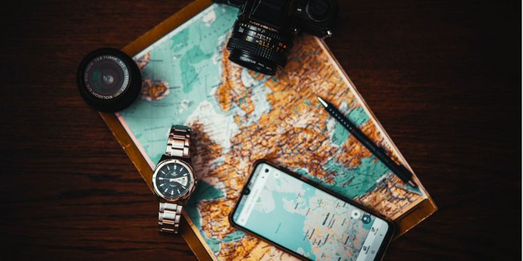 Travel essentials including a passport, boarding pass, compact luggage, and headphones arranged on a map, symbolizing thorough travel preparation.