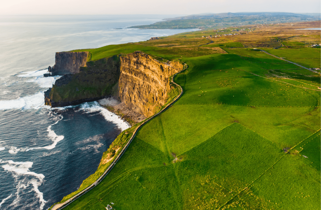 Majestic Cliffs of Moher near Doolin, Ireland, with lush green grass and the Atlantic Ocean, under a dynamic sky.