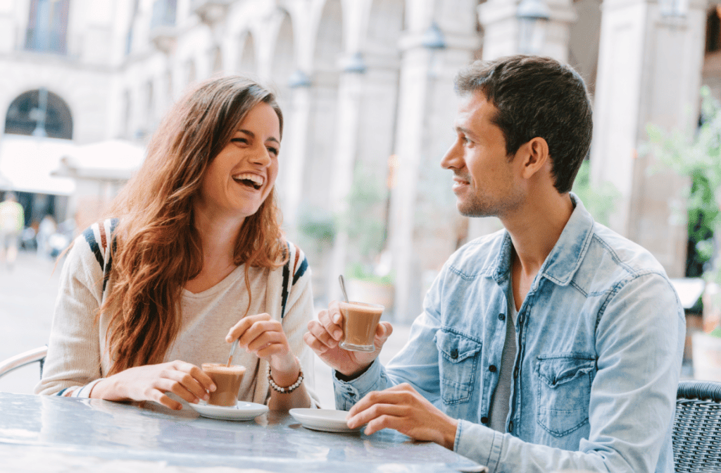 Essential Europe Travel Checklist - A woman and a man enjoying coffee at a European cafe, engaging in cultural exchange.