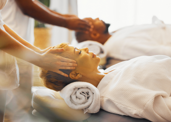Image showing a serene wellness retreat setting with modern architecture, featuring a spacious outdoor area with a tranquil pool surrounded by lush greenery and comfortable lounge chairs, set against a backdrop of a clear blue sky, capturing the essence of relaxation and rejuvenation at a luxury retreat.