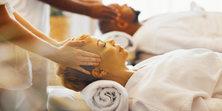 Image showing a serene wellness retreat setting with modern architecture, featuring a spacious outdoor area with a tranquil pool surrounded by lush greenery and comfortable lounge chairs, set against a backdrop of a clear blue sky, capturing the essence of relaxation and rejuvenation at a luxury retreat.